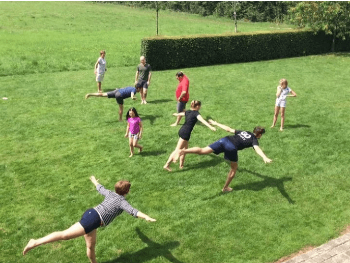 Group outdoor training session — athletes performing lunges and reaches in the grass